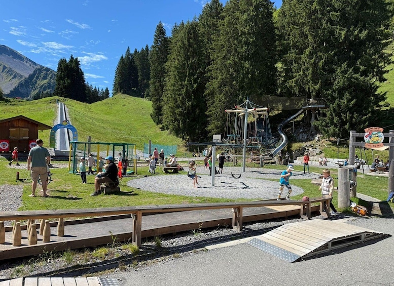 A playground with slides and climbing structures, surrounded by a mountainous landscape. 3