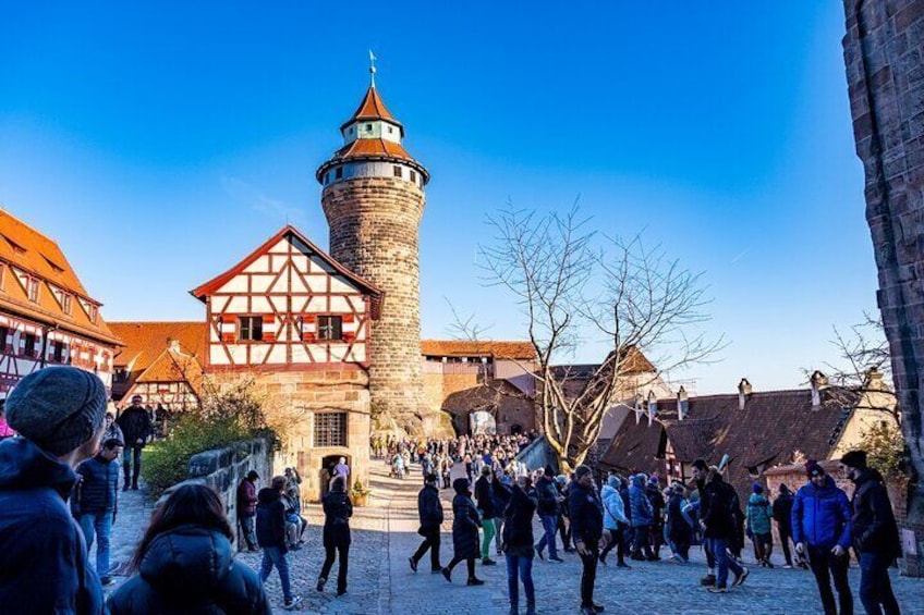 Ein historischer Stadtplatz mit einem markanten Turm und traditionellen Fachwerkhäusern. 4