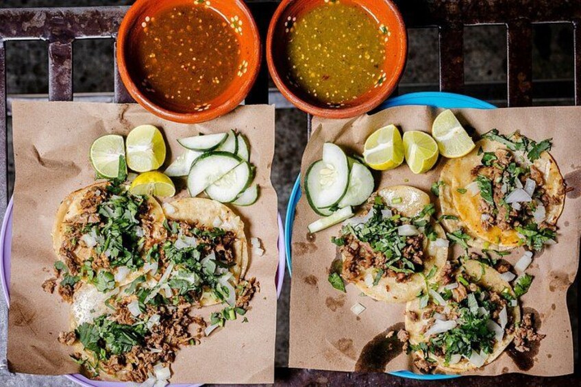 Dos tacos con cuñas de limón y un tazón de salsa. 1