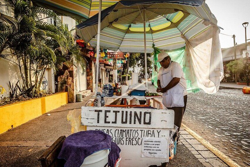 Un vendedor ambulante bajo un paraguas a rayas, ofreciendo comida. 4