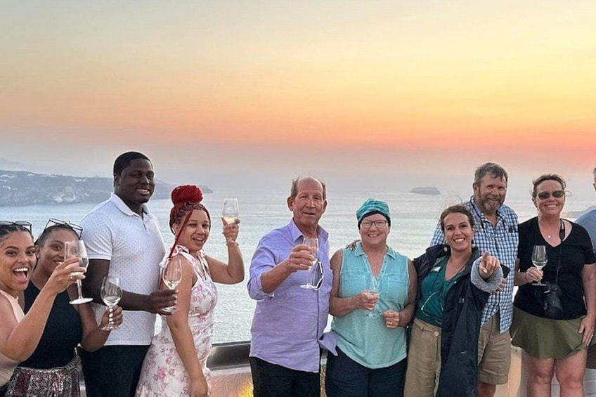 A group of people toasting with wine glasses against a sunset backdrop. 1