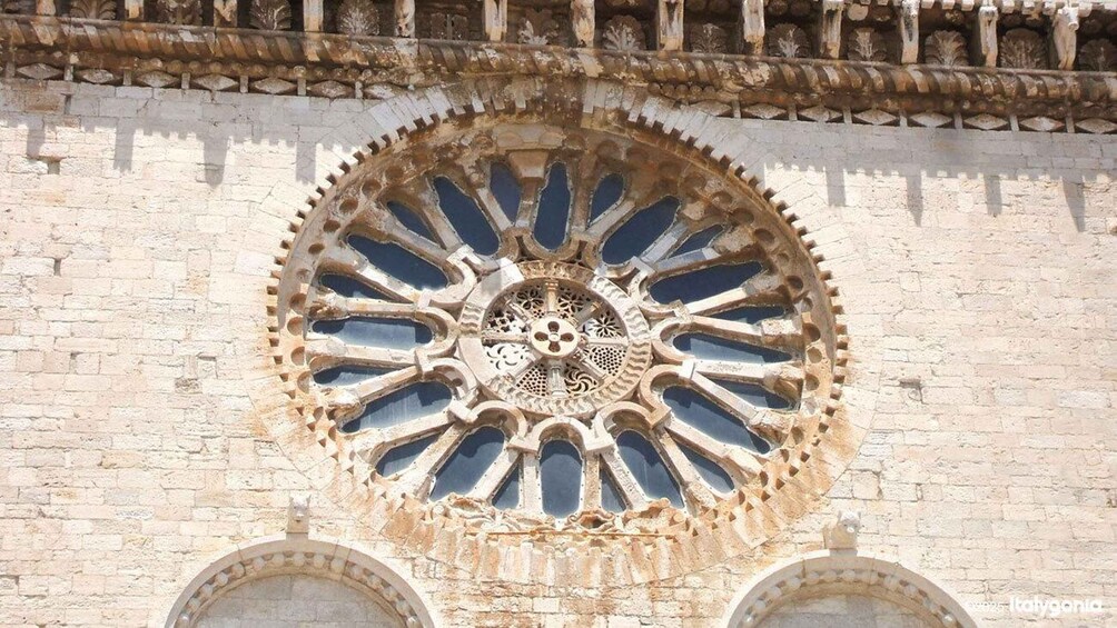 A historic stone building with a large, ornate circular window featuring intricate patterns and a central rose window. 3