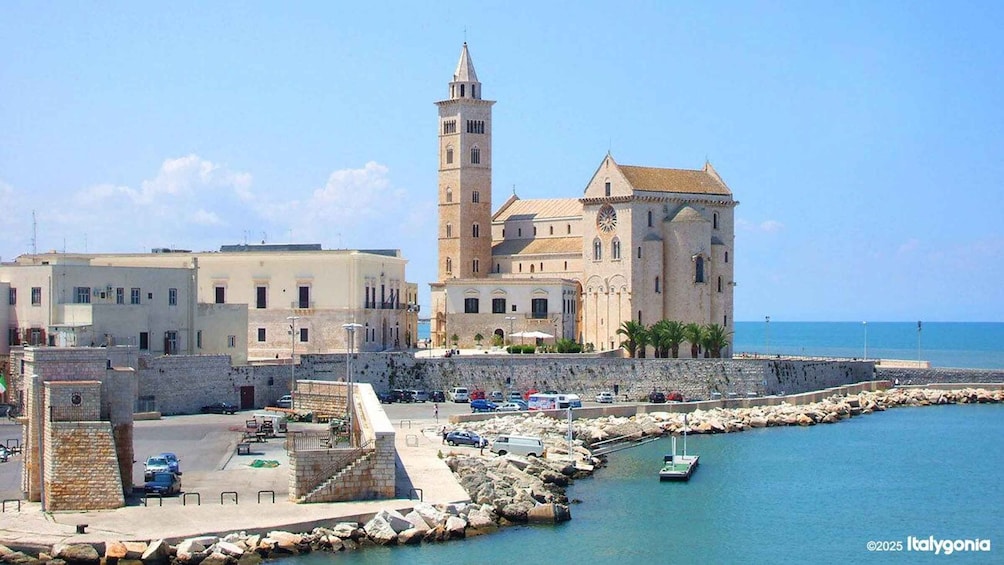 A coastal town with a prominent church, a tower, and a marina with boats. 2
