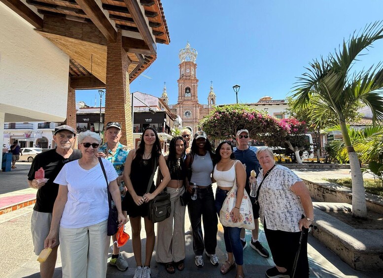 A group of people posing in front of a historic building with a clock tower. 3