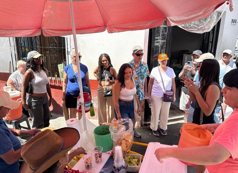 A group of people gathered around a food stall with various food items and drinks. 5