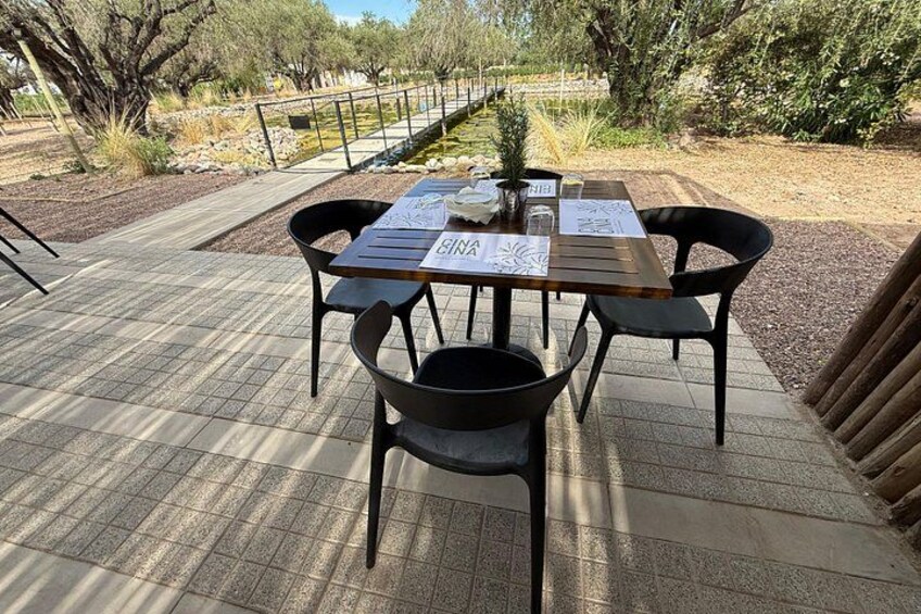 Un espace extérieur aménagé pour les repas, avec une table et des chaises, entouré d’un jardin arboré et agrémenté d’un sentier. 4