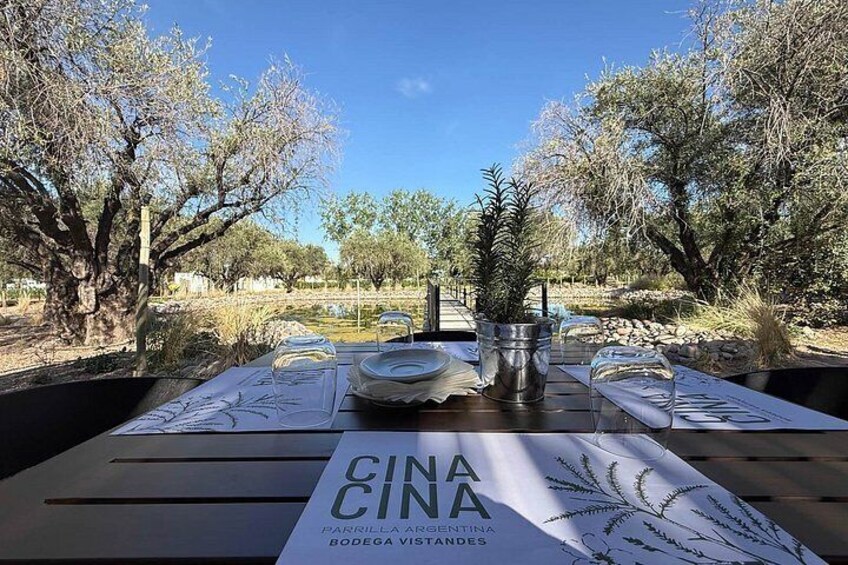 An outdoor dining table set with plates, glasses, and a menu titled 'CINA BODEGA VISTAS.' 1