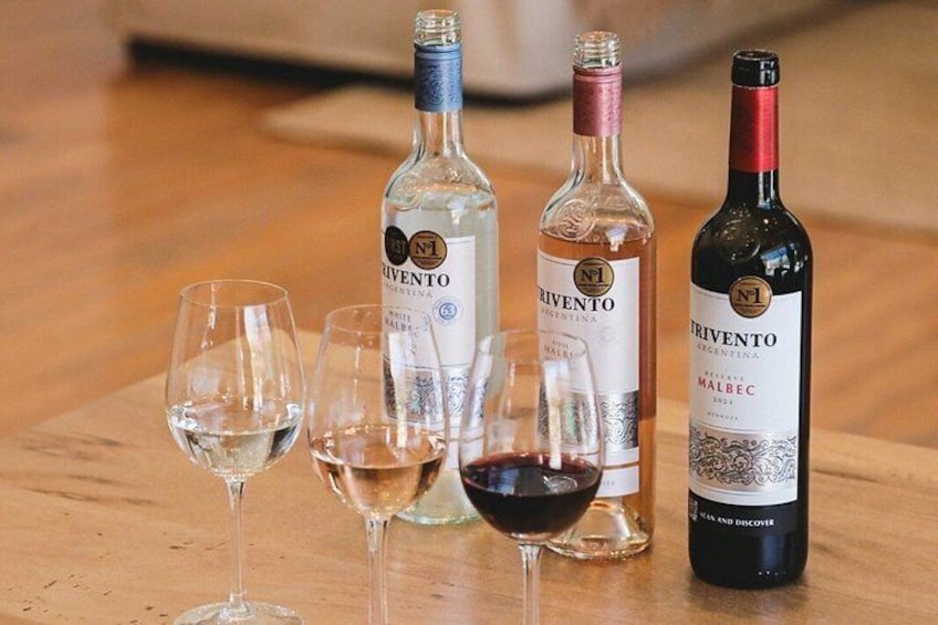 Three bottles of wine and four wine glasses on a wooden table. 5
