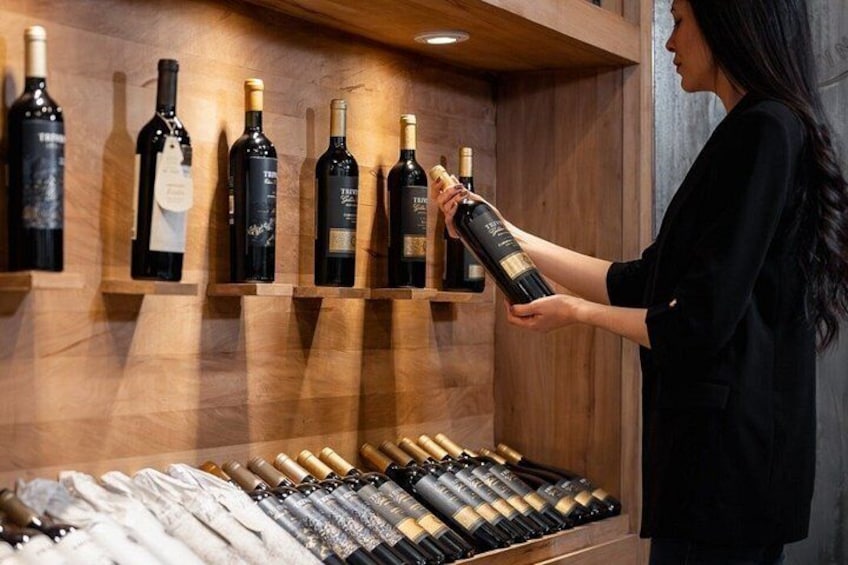 A person selecting a wine bottle from a wooden wine rack. 3