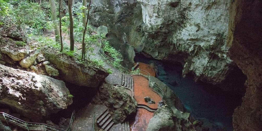 A cave with a wooden walkway and a small pool. 5