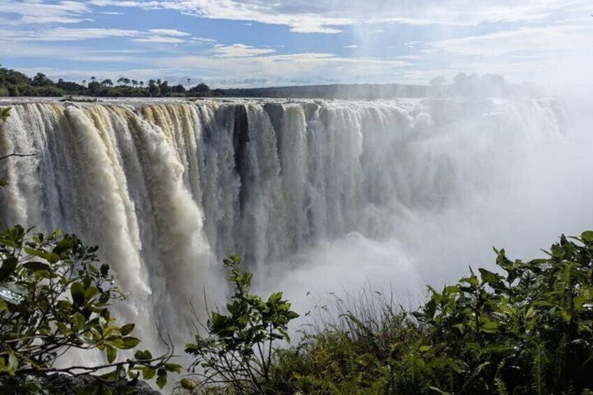 Een grote waterval met verschillende niveaus, omgeven door weelderige begroeiing. 1