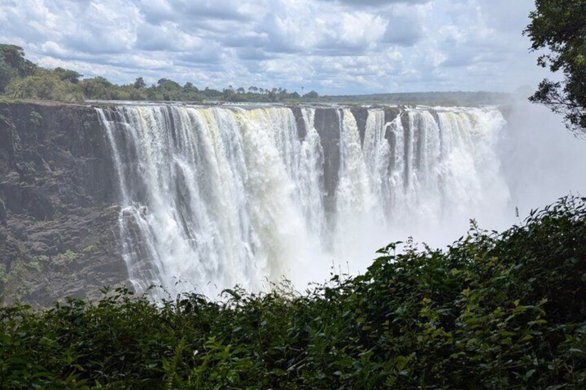 Een grote waterval die over een klif stort, omgeven door groen. 5