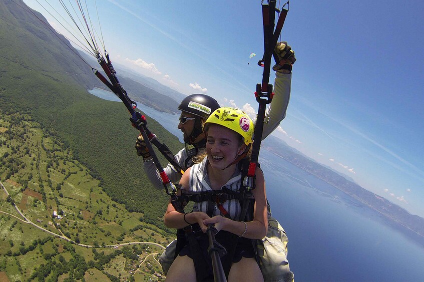 A person paragliding over a mountainous landscape with a body of water below. 1