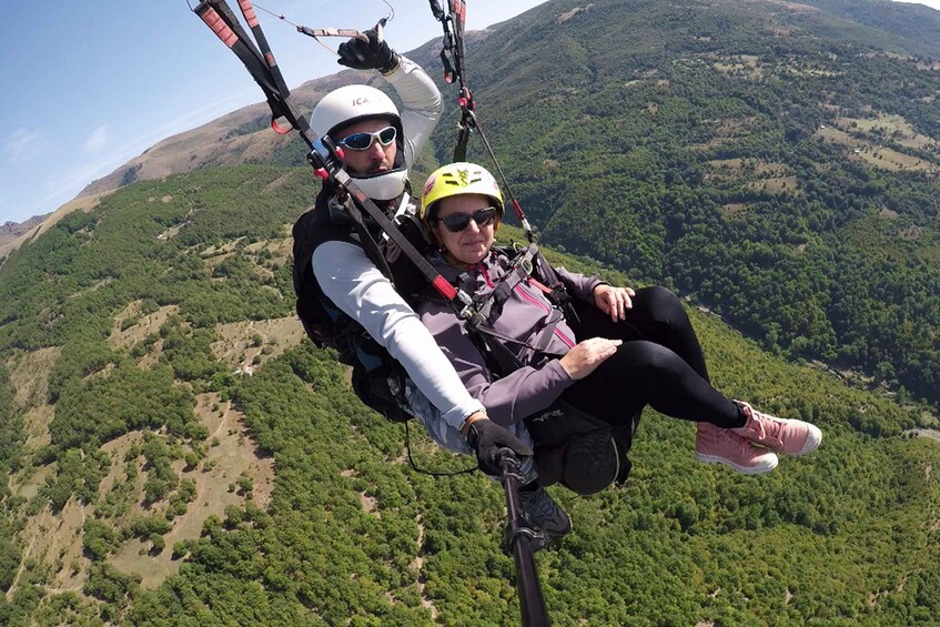 Two people paragliding over a mountainous landscape. 2