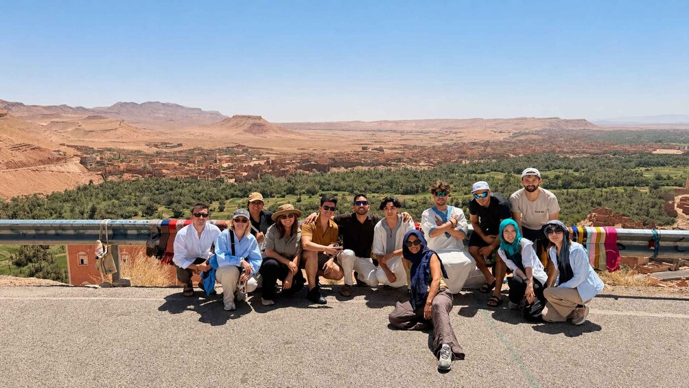 A group of people posing for a photo in a desert landscape with mountains in the background. 3