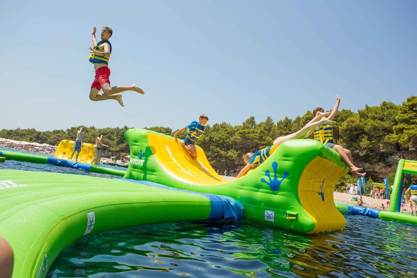 A water park with inflatable slides and a person jumping into the water. 1