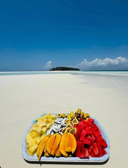 A beach with a plate of fruit in the foreground and a distant island. 4