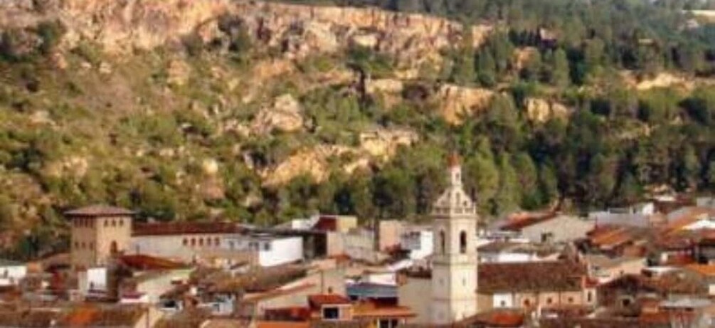 A town nestled in a valley with a prominent church tower and surrounding buildings. 3