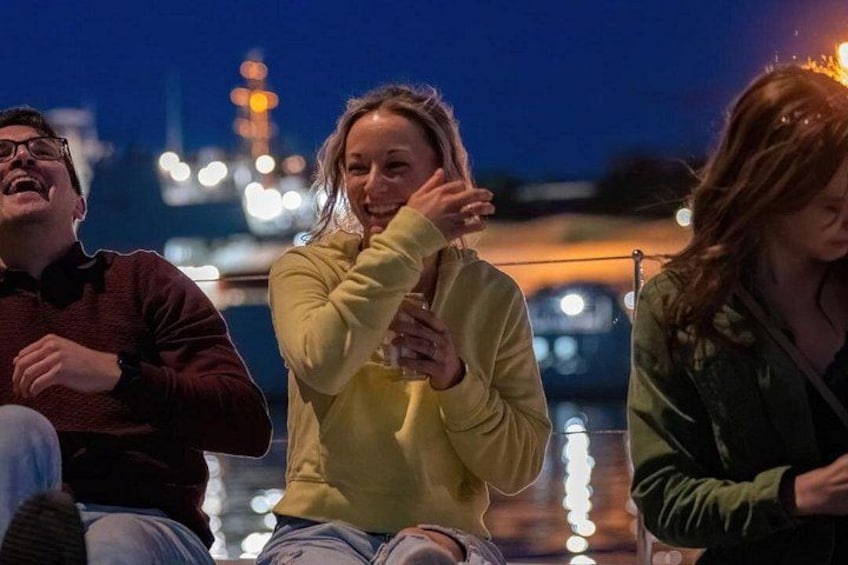 Una persona con un suéter amarillo gesticula, con un paisaje urbano y luces de fondo. 2