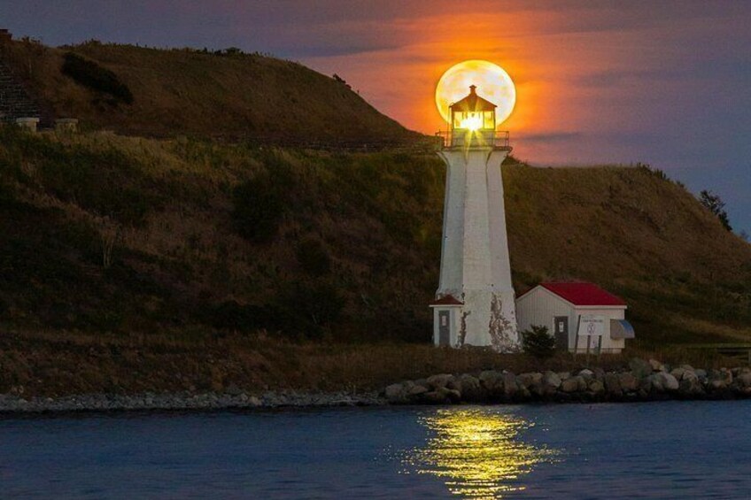 Un faro en una colina con un atardecer de fondo. 2