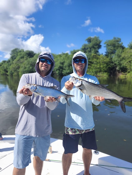 Two people on a boat holding fish. 4