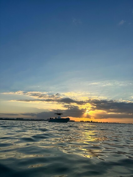 A boat on calm water with a sunset in the background. 3