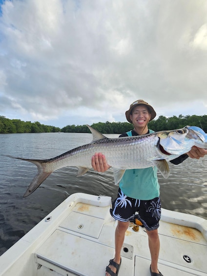 A person holding a large fish on a boat. 5
