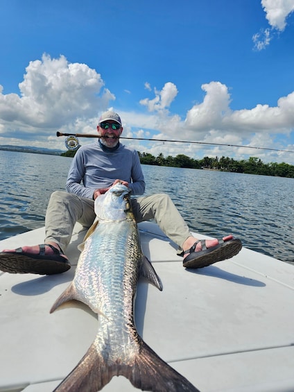 A person sitting on a boat holding a large fish. 2