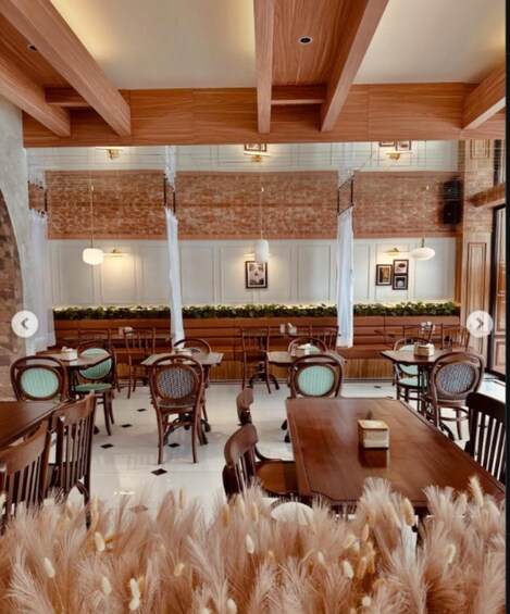A restaurant interior with wooden beams, brick walls, and a long communal table. 2