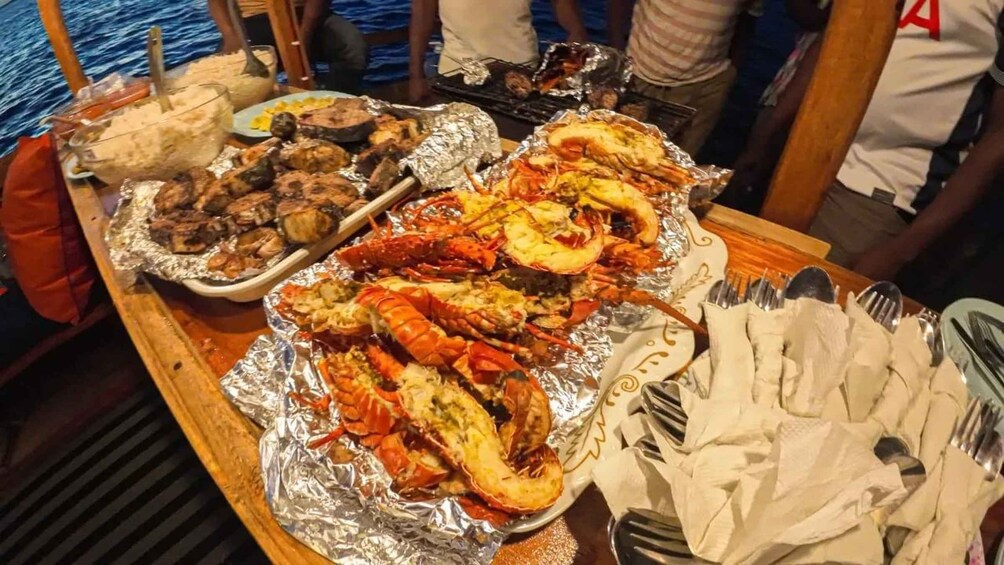 Une table garnie de fruits de mer, notamment de homards et de crevettes, sur un bateau. 2