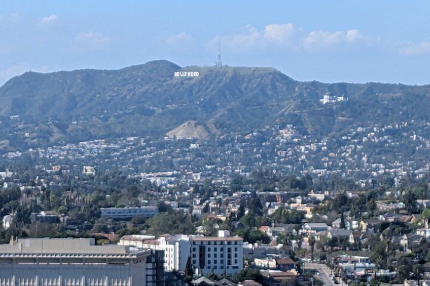 Un paisaje urbano con una colina destacada que dice 'Hollywood' al fondo. 1