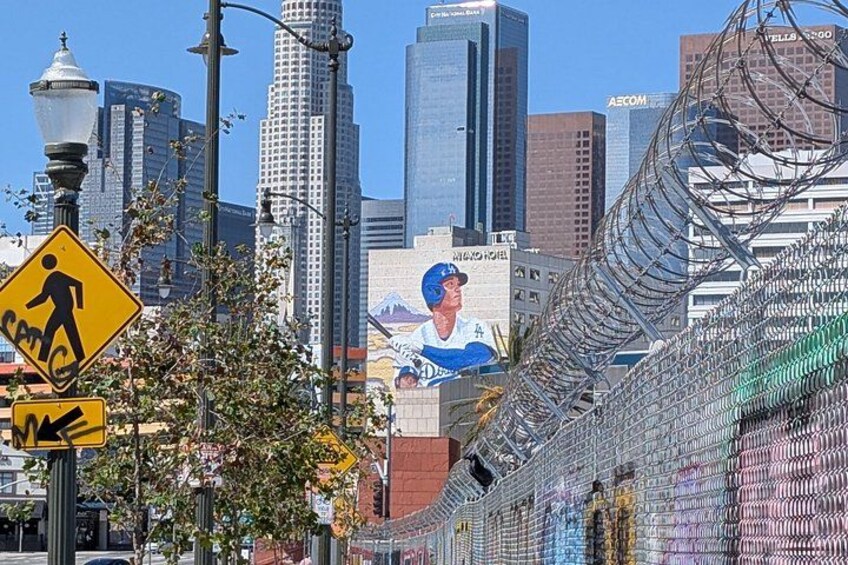 Un paisaje urbano con edificios altos, una señal de paso para peatones y un mural en una pared. 2