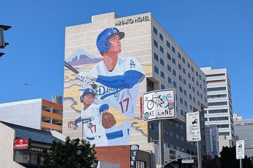 Un mural de un jugador de béisbol en un edificio, una señal de carril bici y un hotel llamado 'MIAMI HOTEL'. 5