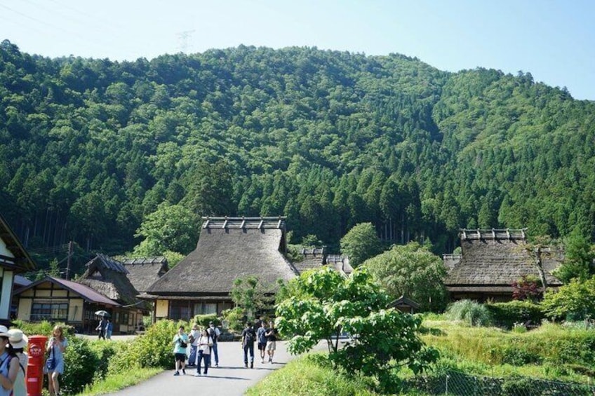 A traditional Japanese village with thatched-roof houses and a forested mountain backdrop. 4