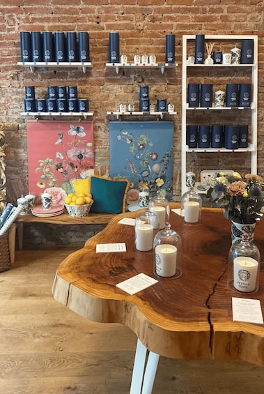 A wooden table with candles and a vase of flowers, surrounded by shelves with candles and decorative items. 5