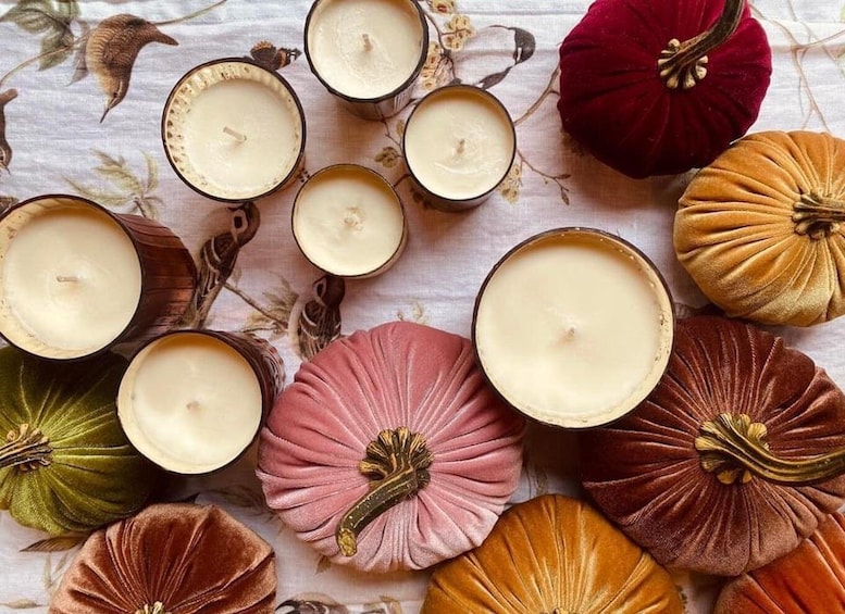 A collection of candles in various shapes and sizes, surrounded by decorative gourds. 3