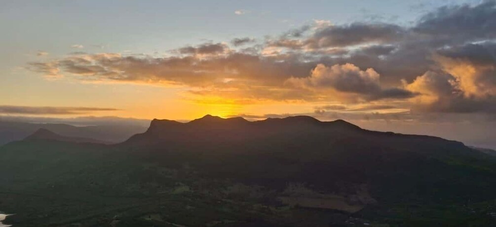 A mountain range at sunset with clouds in the sky. 1