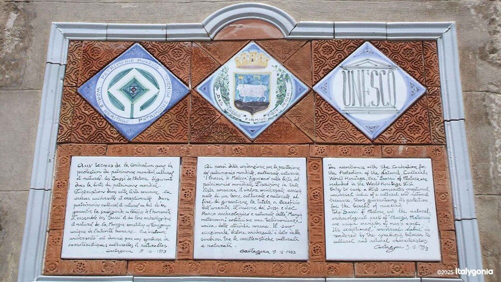 A wall with three plaques, each with a different emblem and text in French. 3