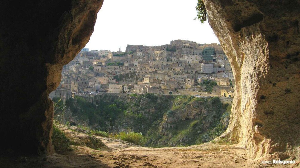 A view of a densely packed town through a natural rock formation. 1