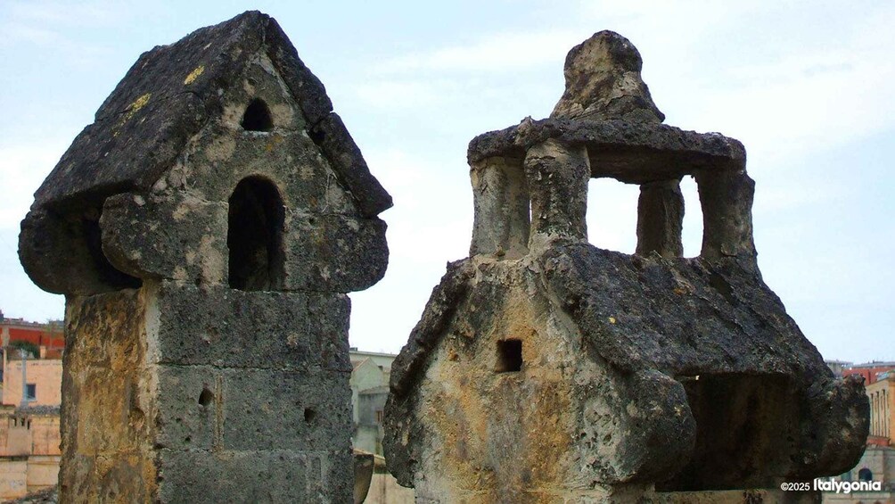 Two ancient stone structures with conical roofs and arched openings. 2