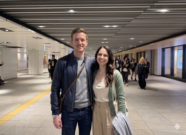A man and woman standing in a modern indoor corridor with tiled floors and overhead lighting. 4