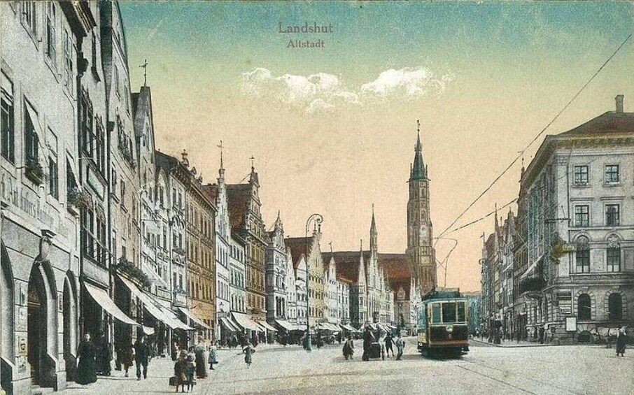A historic European town with a prominent church tower, a tram, and traditional buildings. 3