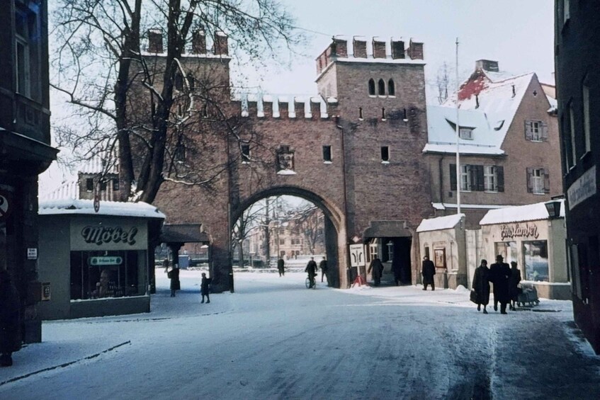 A snow-covered street with a medieval-style archway, a brick building labeled 'Motel,' and a building with a sign 'Café Napier.' 2