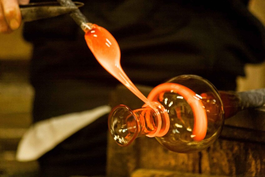 A glassblowing process with molten glass being shaped by a tool. 5