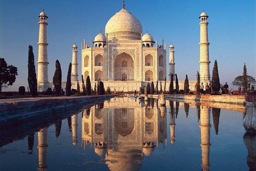 The Taj Mahal with its reflection in the water, four minarets, and surrounding trees. 4