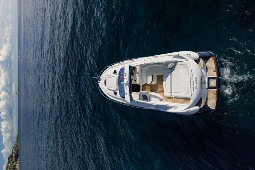 A white motorboat on a calm sea with a wooden deck and a cabin. 3