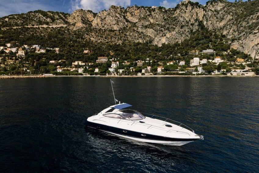 A white speedboat on calm water with a mountainous coastline in the background. 2