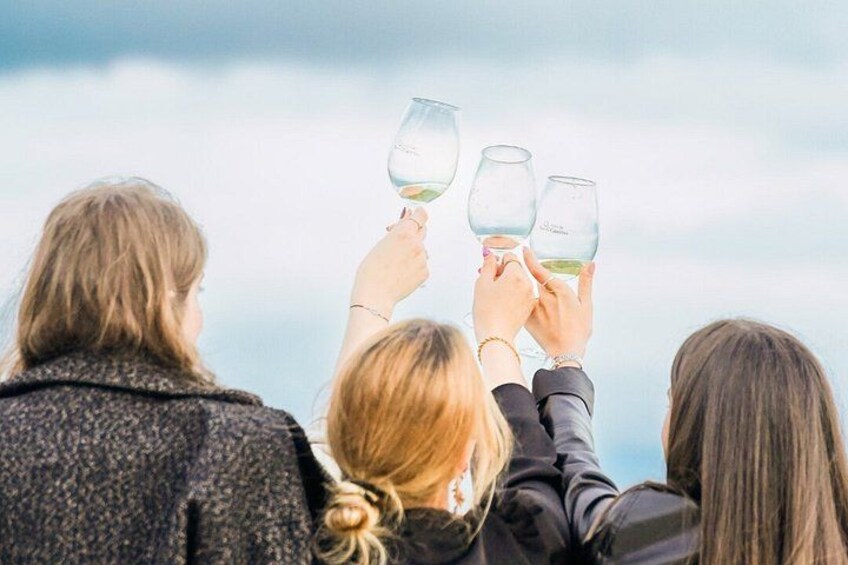 Three people holding wine glasses against a cloudy sky. 1
