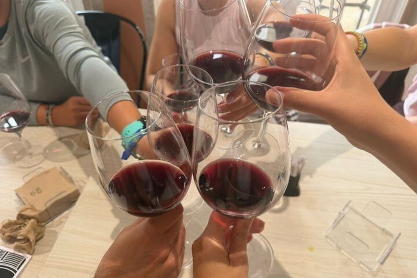 A group of people toasting with wine glasses filled with red wine. 2