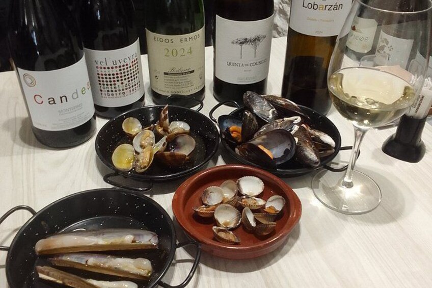 A table with wine bottles, clams, and a glass of white wine. 1